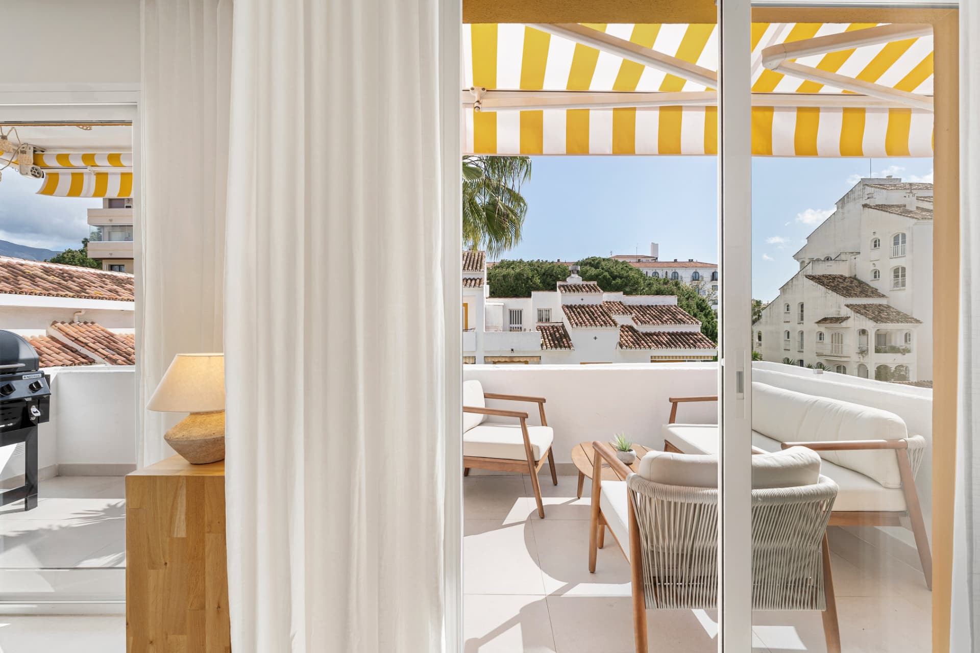 Sunlit terrace with striped awning seen from inside the Los Corales residence